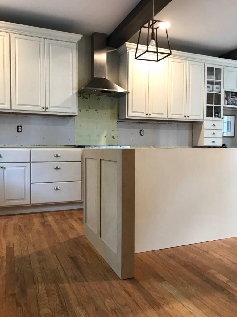 White Kitchen Renovation. HanStone Quartz, Montauk. White painted cabinets, black hardware