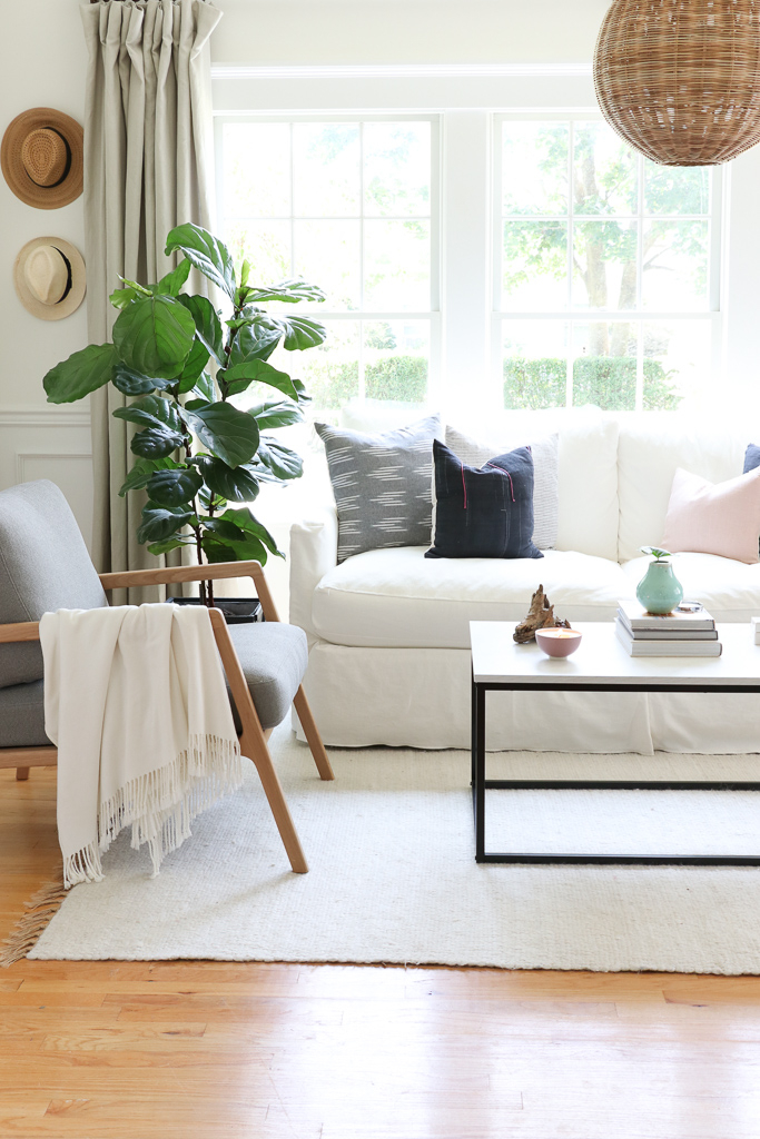 Denman Chair Article, White Slipcovered sofa, Woven Shade, White Walls, City Farmhouse & Co Pillows, Hats on Wall, Indigo Pillows