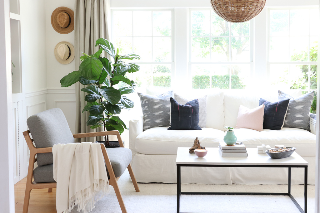 Denman Chair Article, White Slipcovered sofa, Woven Shade, White Walls, City Farmhouse & Co Pillows, Hats on Wall, Indigo Pillows