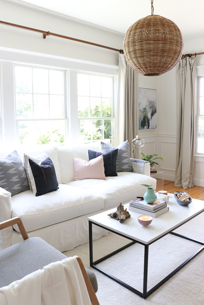 Denman Chair Article, White Slipcovered sofa, Woven Shade, White Walls, City Farmhouse & Co Pillows, Hats on Wall, Indigo Pillows