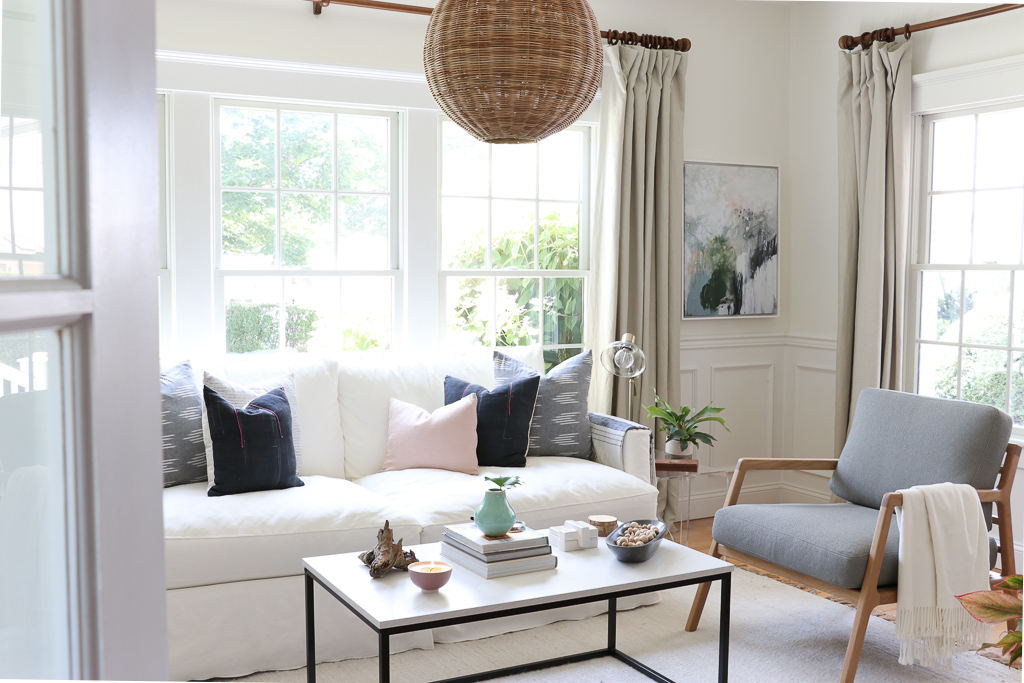 Denman Chair Article, White Slipcovered sofa, Woven Shade, White Walls, City Farmhouse & Co Pillows, Hats on Wall, Indigo Pillows