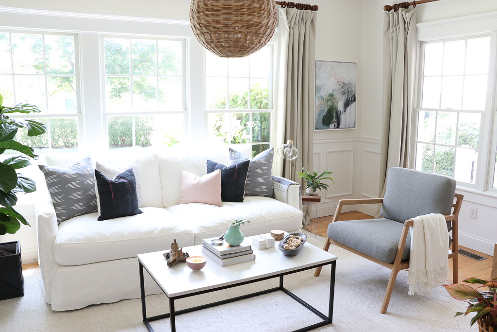 Denman Chair Article, White Slipcovered sofa, Woven Shade, White Walls, City Farmhouse & Co Pillows, Hats on Wall, Indigo Pillows