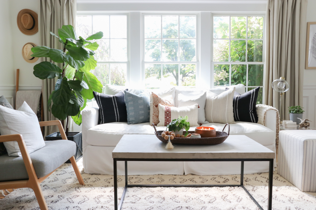 City Farmhouse fall den. Pure White walls and white slipcovered sofa.