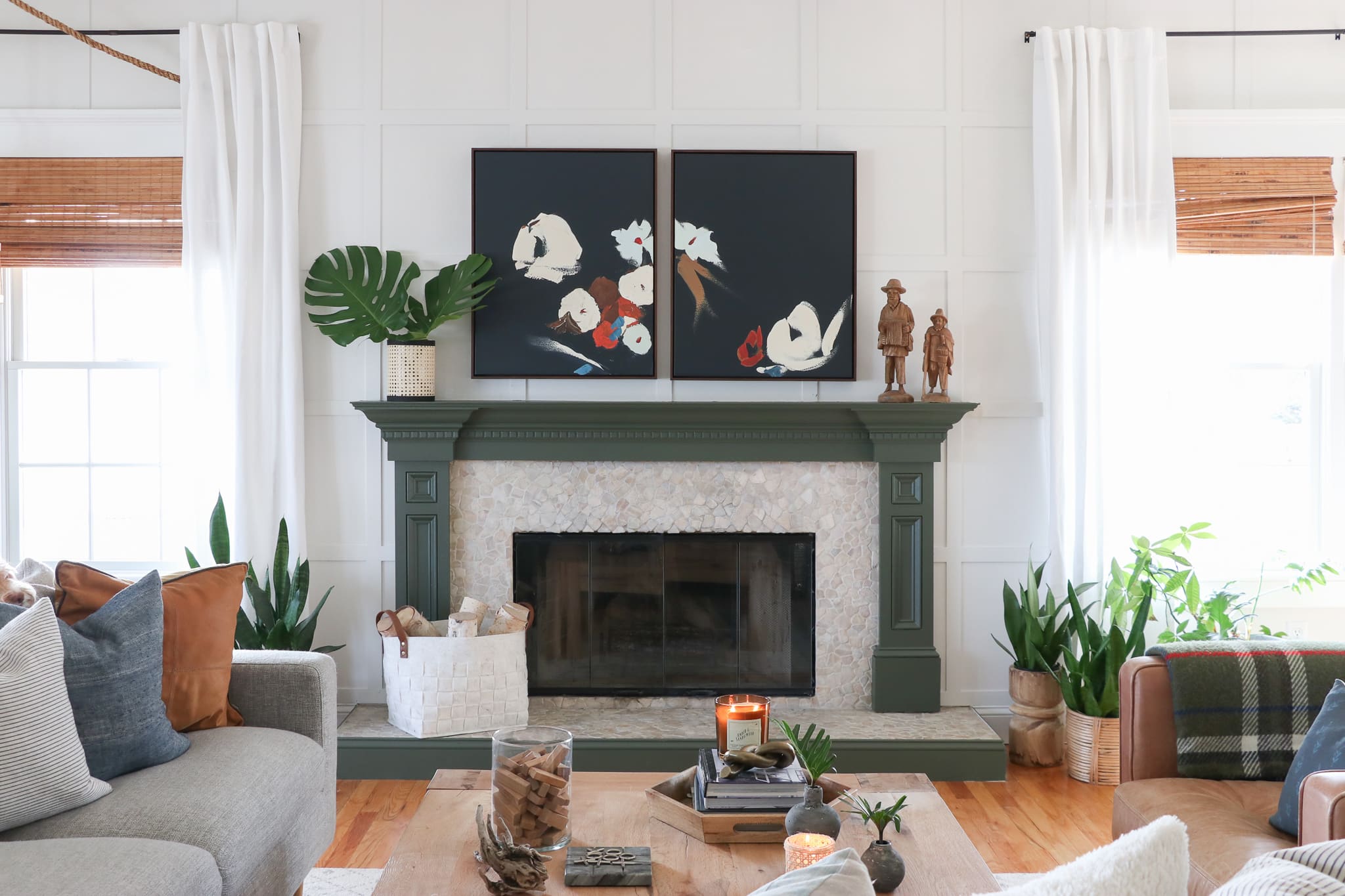 Woven shades in family room. Dark green painted mantle, sofa Interior Define, botanical art from Minted